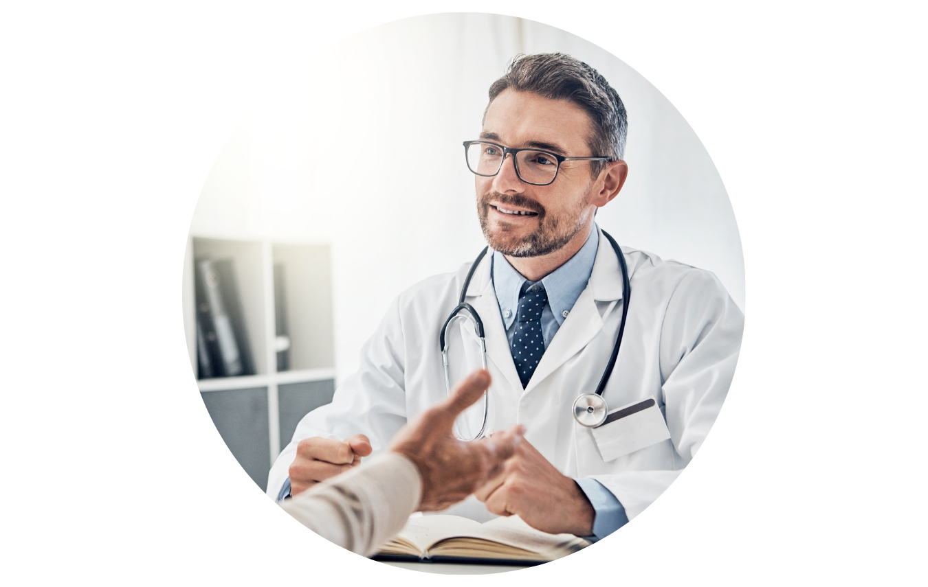 Ein Arzt sitzt in seiner Praxis am Schreibtisch und führt ein Patientengespräch mit einem älteren Herrn.